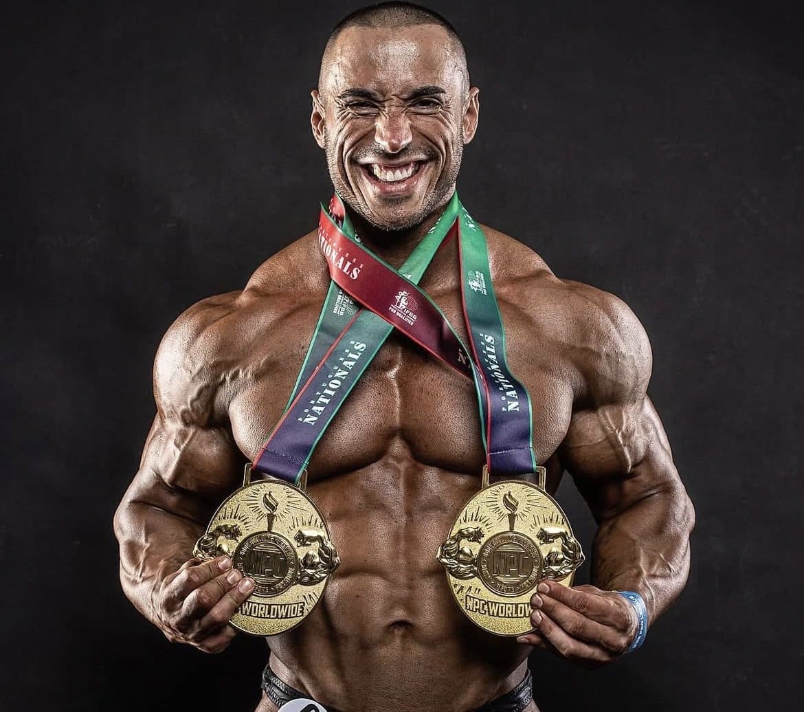 Miguel Pinto a sorrir em palco, em tronco nu, com duas medalhas ao peito